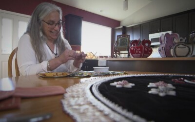 Woman seated at kitchen table doing Iroquois Beadwork