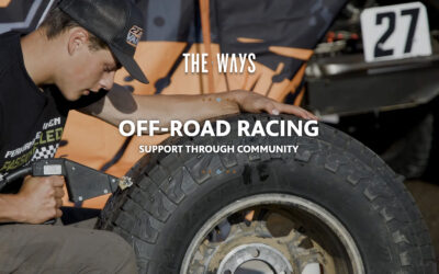 Person repairing large off-road tire with tool, text “THE WAYS OFF-ROAD RACING SUPPORT THROUGH COMMUNITY” and number 27 in background